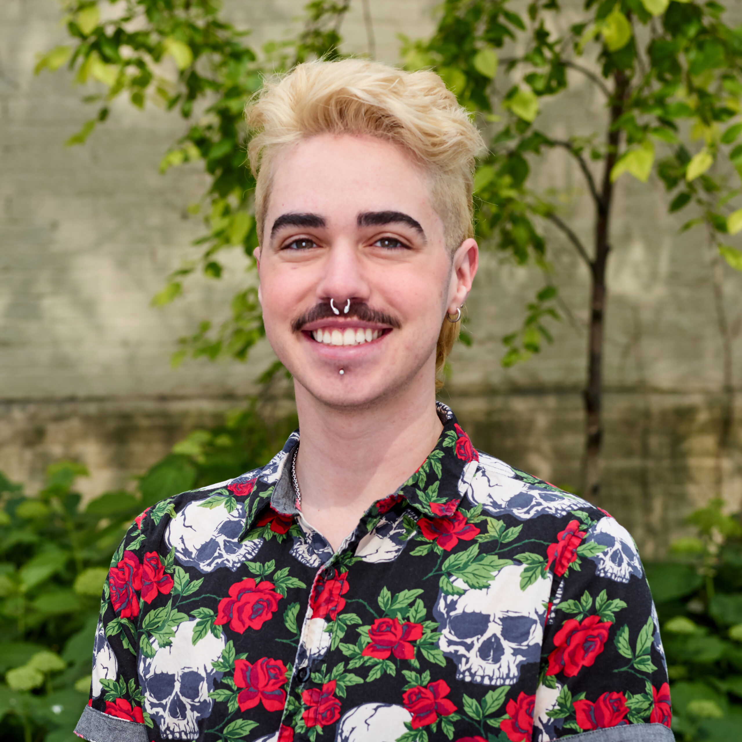 Vaughn outdoors smiling with colorful shirt featuring rose and skull illustrations