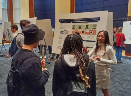 Scientist discussing her poster with visitors