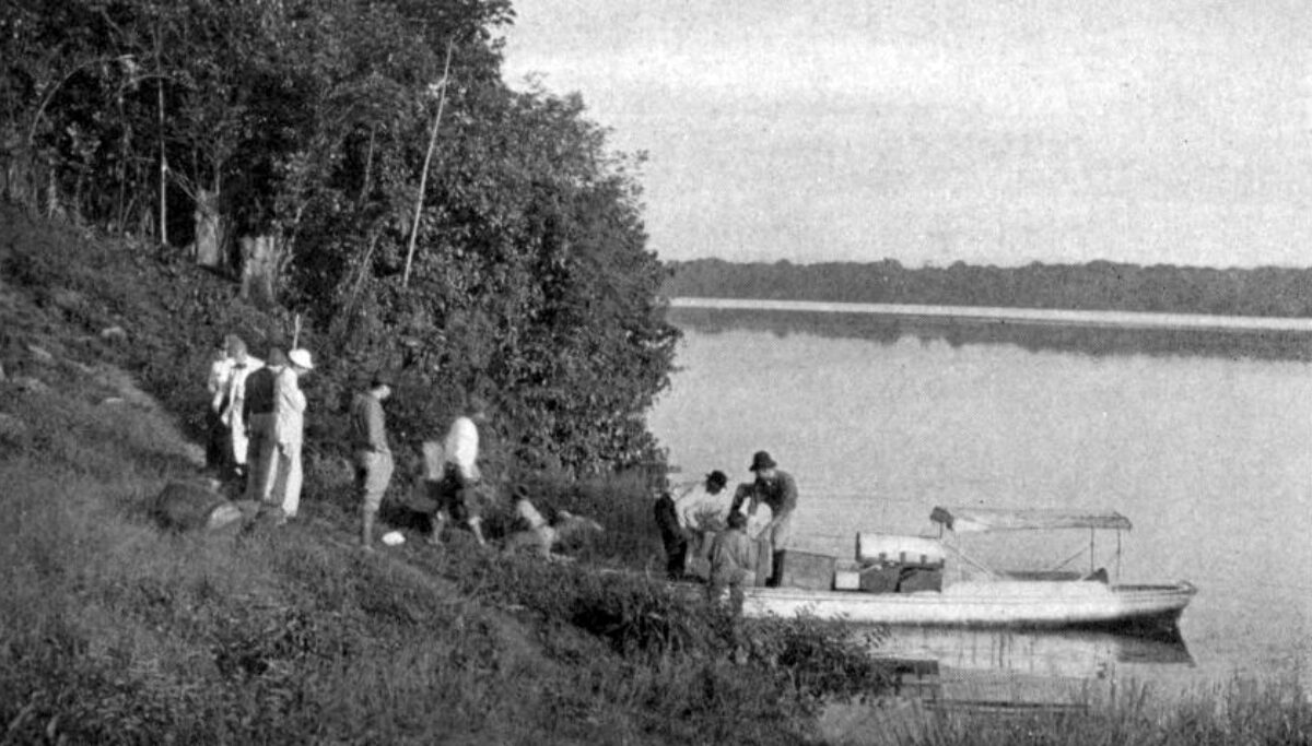 Black and white photo men loading a small boat