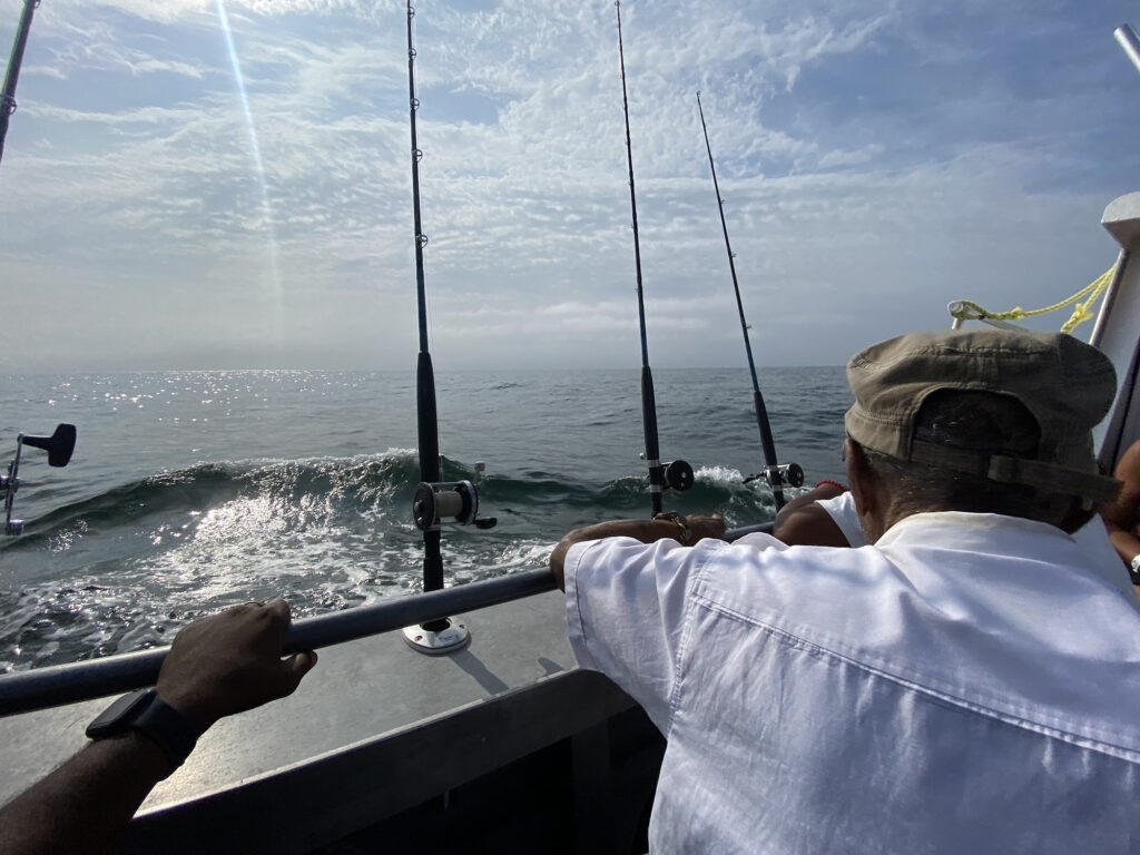 Digital photo of the back of the head of a man fishing from a boat