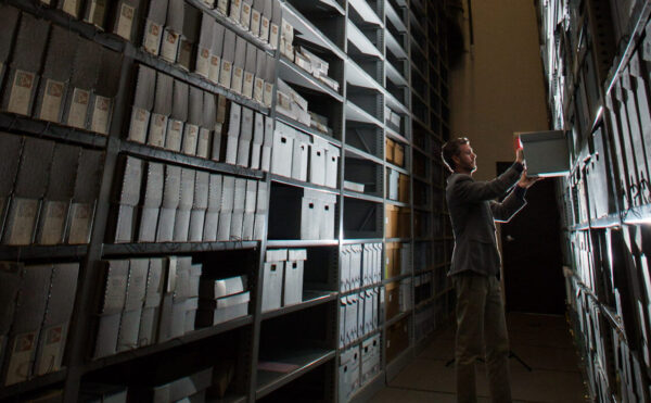 man standing among stacks of high shelves