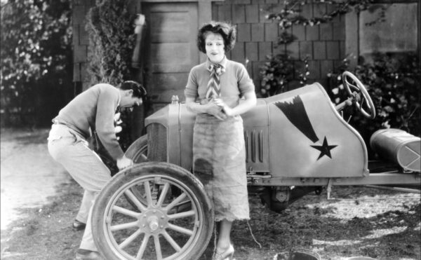 Clara Bow in front of a car being repaired