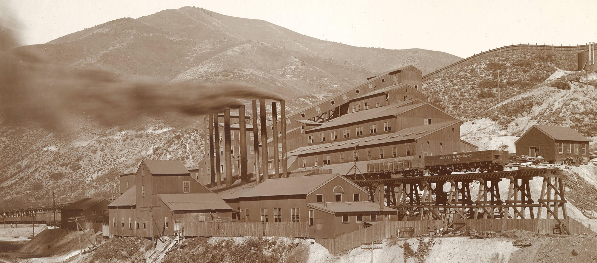 Black and white landscape photo of mining complex with smoking stacks