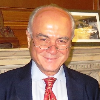 Kenan E. Sahin wearing glasses mid-nose, navy jacket, white shirt, red and gold tie