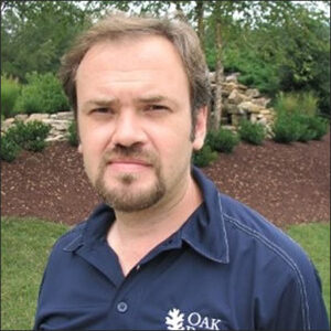 Sergiy Kalnaus outdoors, with goatee and navy blue polo with Oak Ridge National Laboratory logo