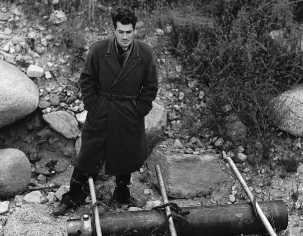 Photo of man standing near rocks and a canister