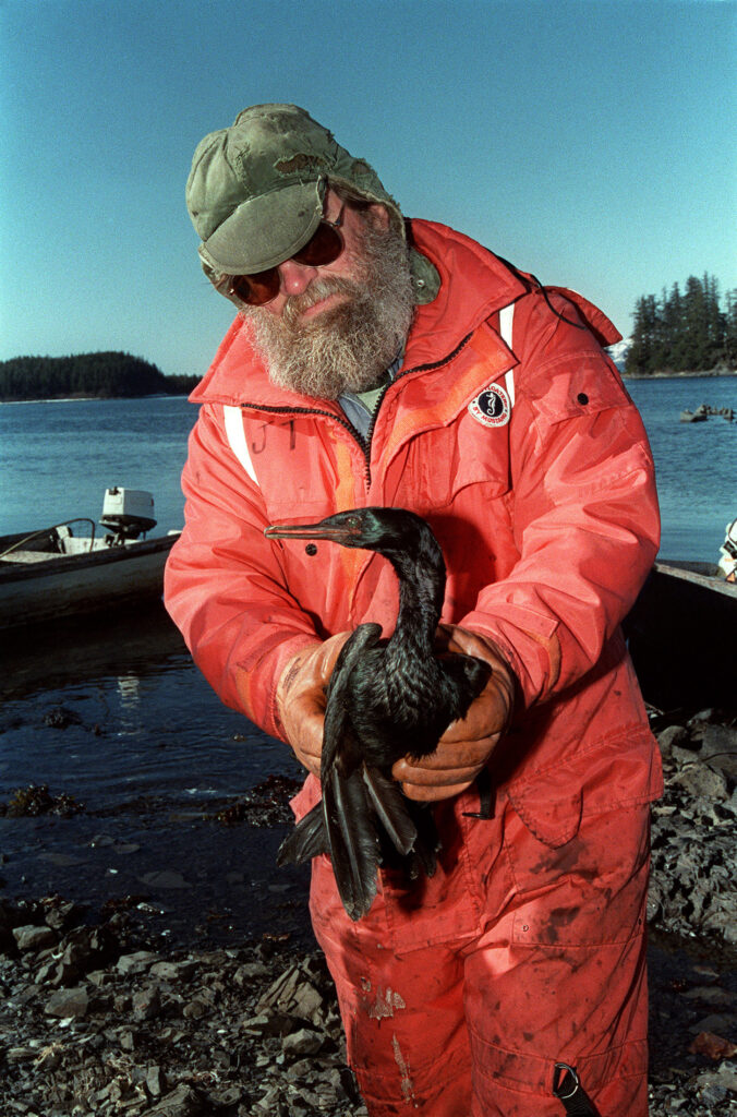 Man in coveralls holding a large bird