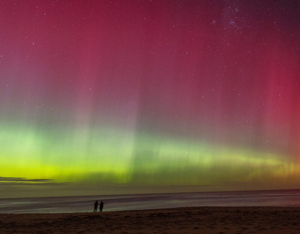 Color photograph of a vivid aurora in the sky over a beach