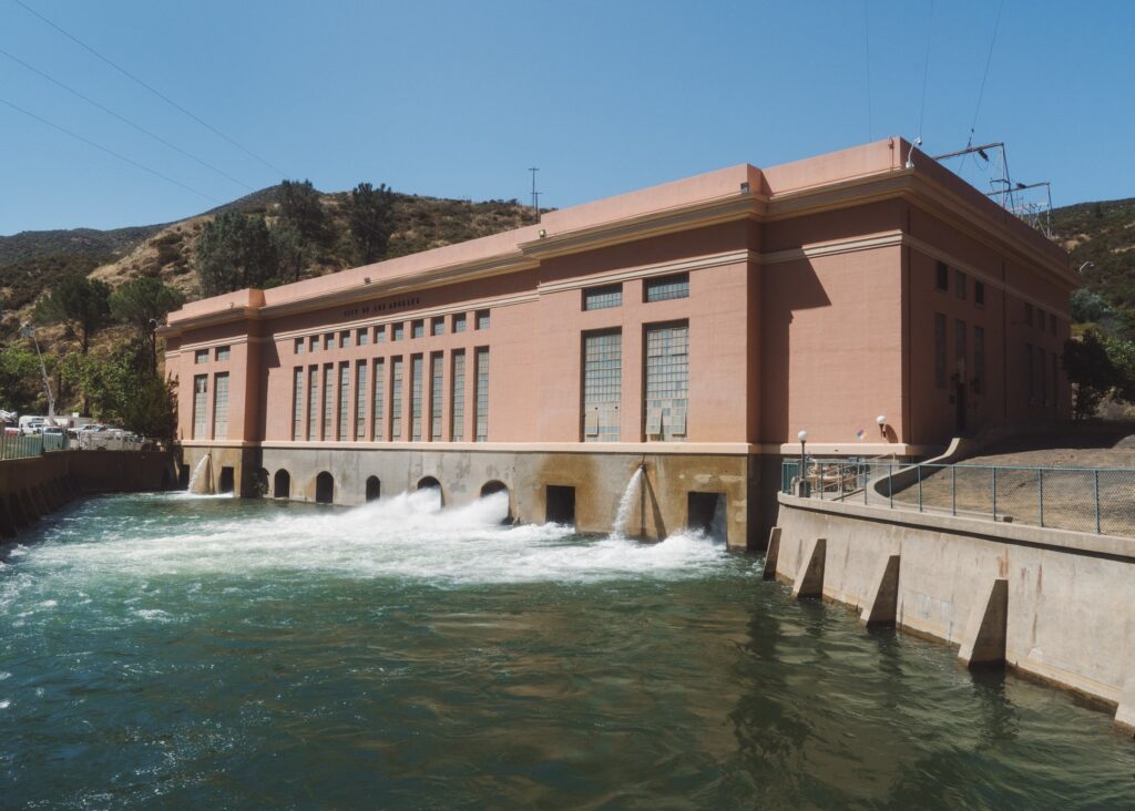 Low red stucco building with water flowing at bottom into a small reservoir