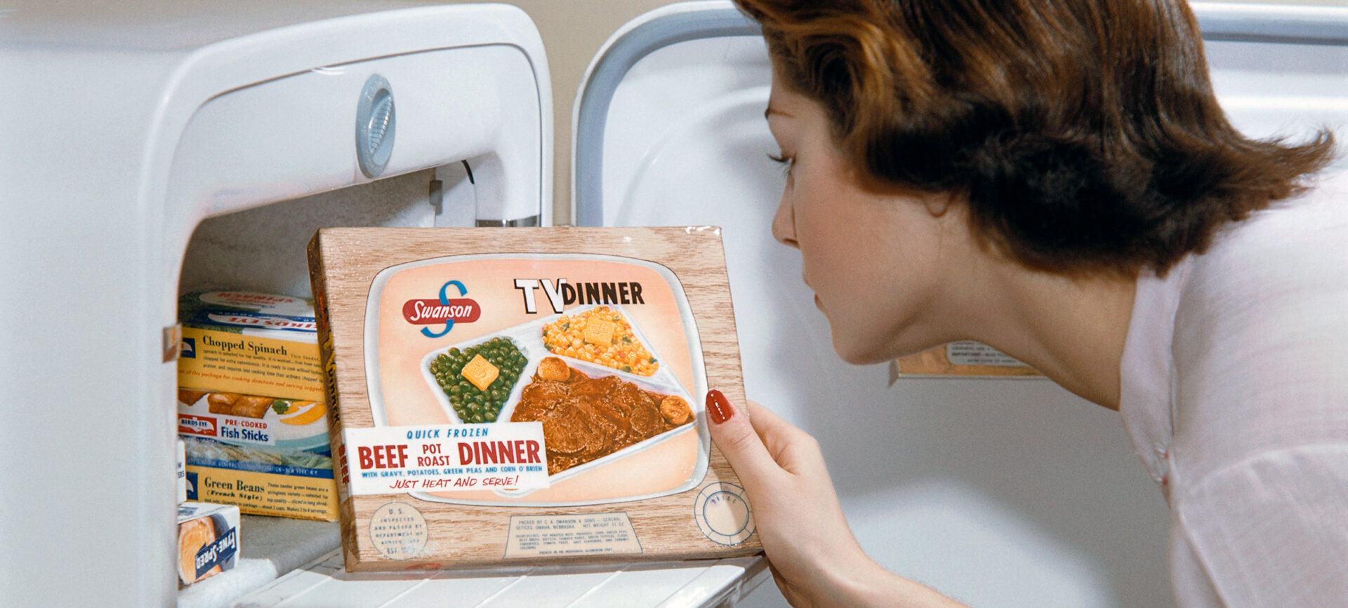A woman examines a TV dinner box she has taken from the freeze