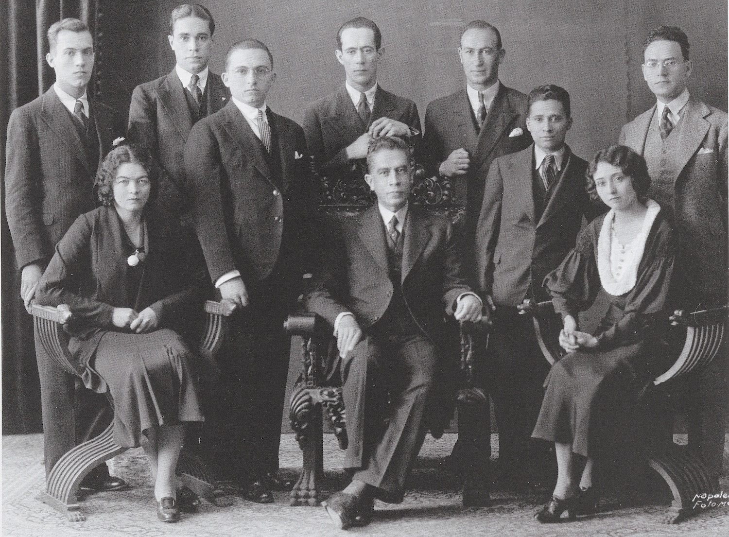 black and white photo of people standing and sitting in a group
