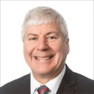 Bruce DeBruin, smiling, suit and tie, white background