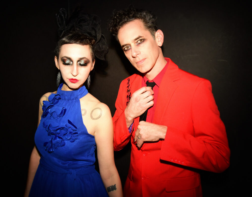 Ellia Bisker and Jeff Morris wearing eclipse glasses in a dark studio