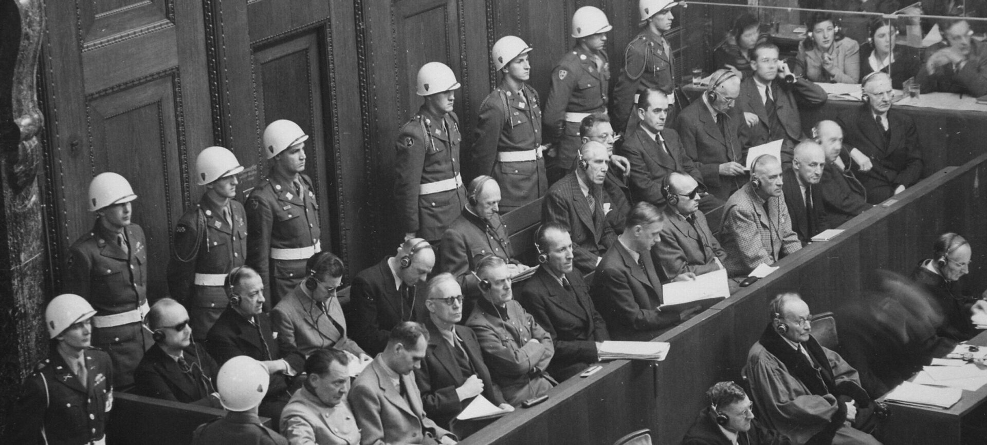 Defendants sitting in blocked off area in court surrounded by military police