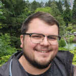 man smiling, wearing glasses, outdoors