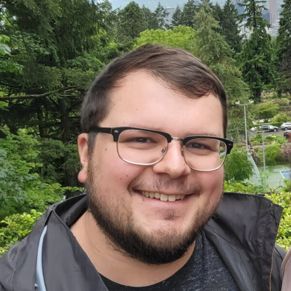 man smiling, wearing glasses, outdoors