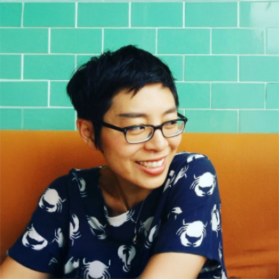 woman in glasses, smiling, looking to the side, wearing shirt with crab pattern