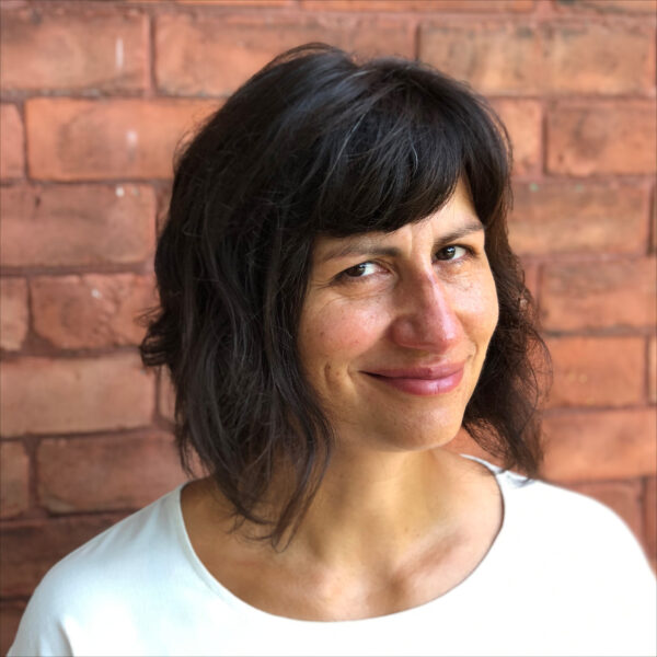 woman in white shirt in front of brick wall