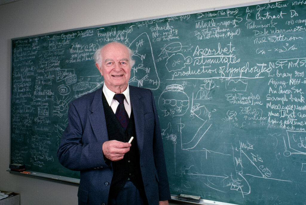 Older man at chalkboard covered in writing
