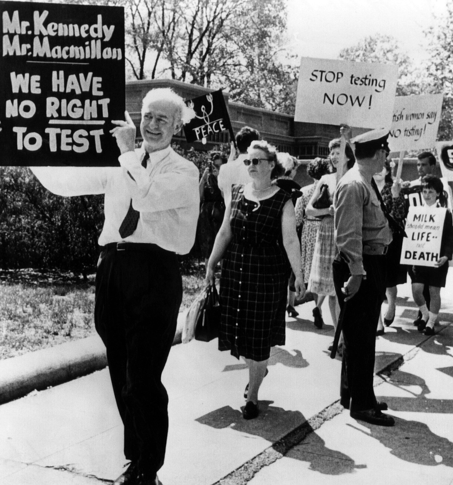 Older man holding protest sign at front of a picket line