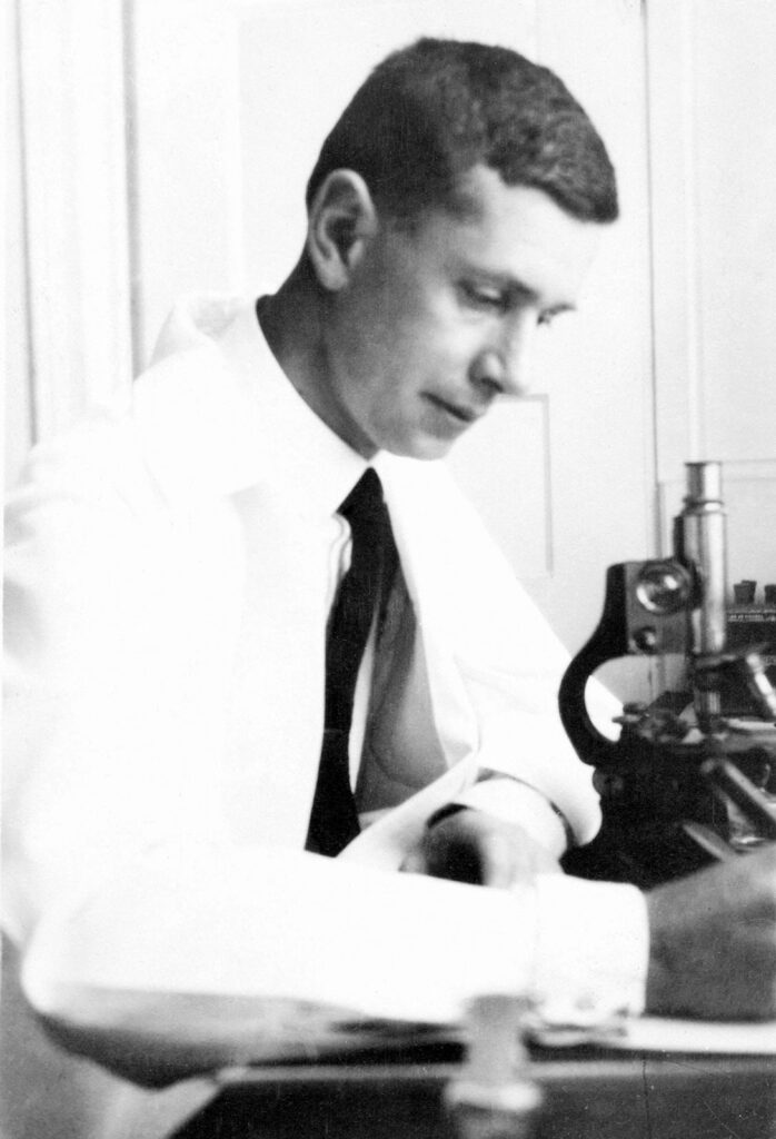 Young man at lab bench with microscope