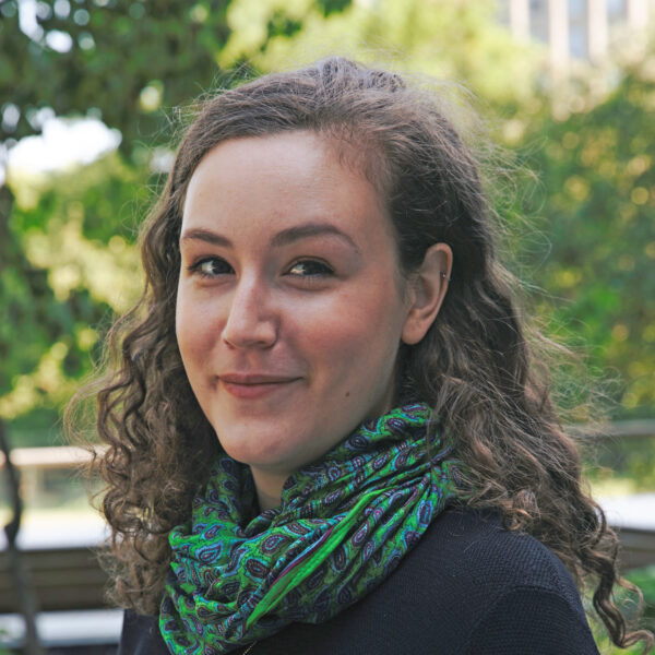 woman outdoors turned 3/4, wearing green scarf
