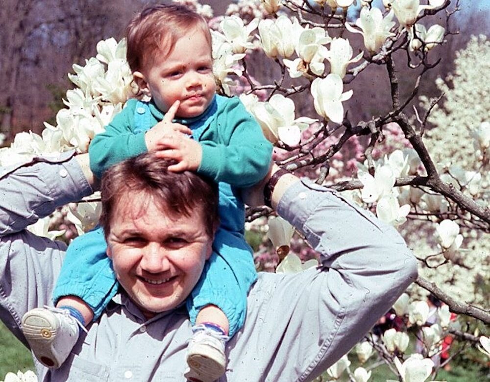 color photo of a man with a baby on his shoulders