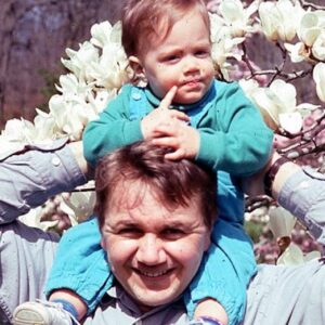 color photo of a man with a baby on his shoulders