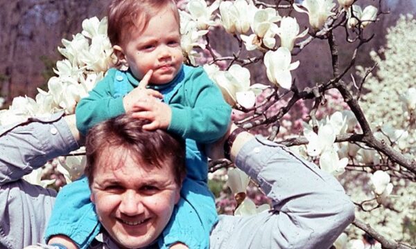 color photo of a man with a baby on his shoulders