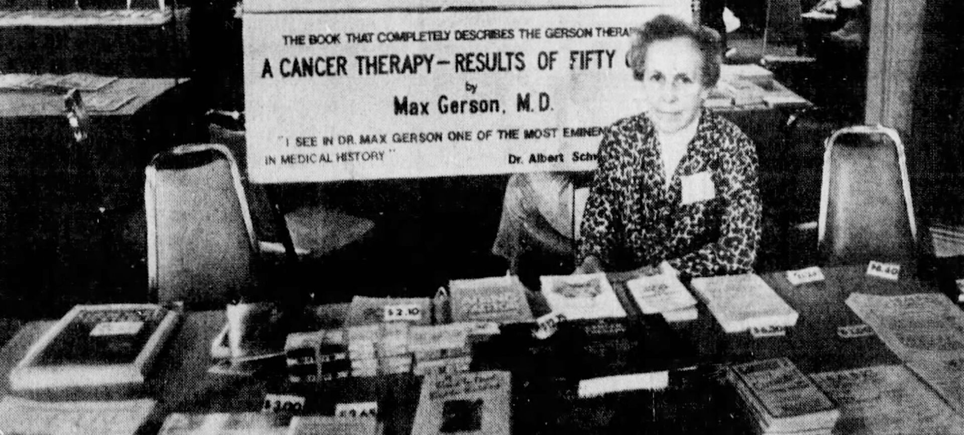 Newspaper photo clipping of a woman seated at a table selling book with a sign titled “Gerson Therapy” above