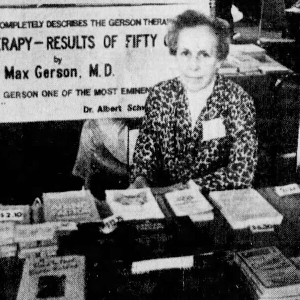 Newspaper photo clipping of a woman seated at a table selling book with a sign titled “Gerson Therapy” above