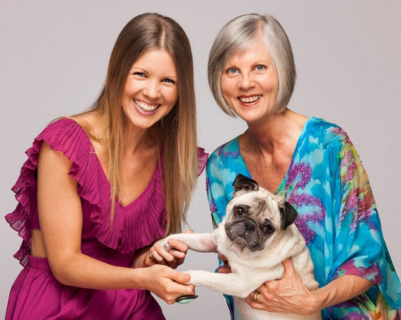 Photo of two women smiling and holding a pug