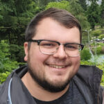 man smiling, wearing glasses, outdoors
