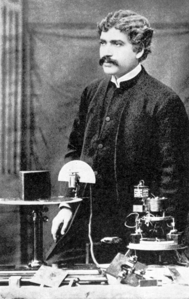 Old black and white photo of a man standing behind scientific instruments