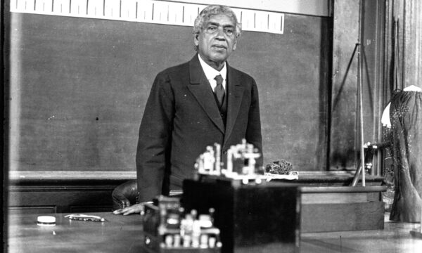 Black and white photo of older man behind a classroom lecturn