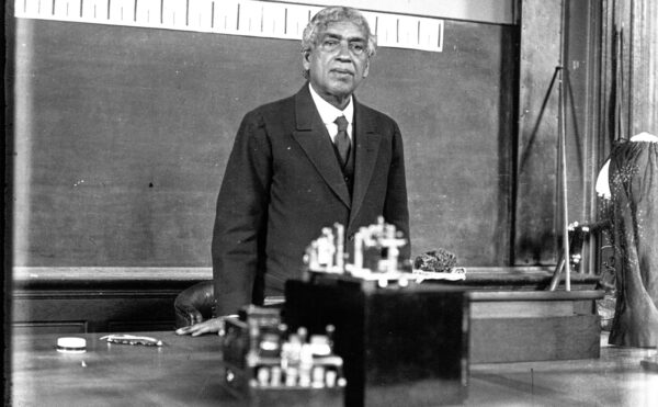 Black and white photo of older man behind a classroom lecturn