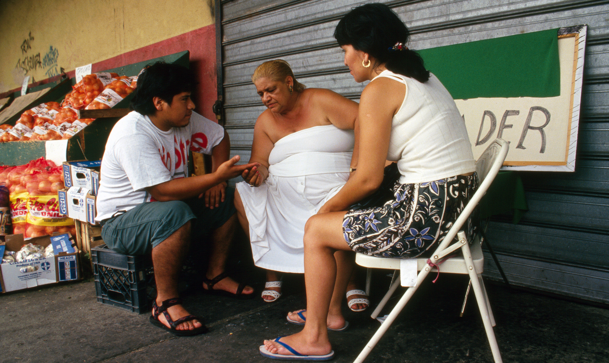 Older woman reading the palm of a young man while a young woman looks on