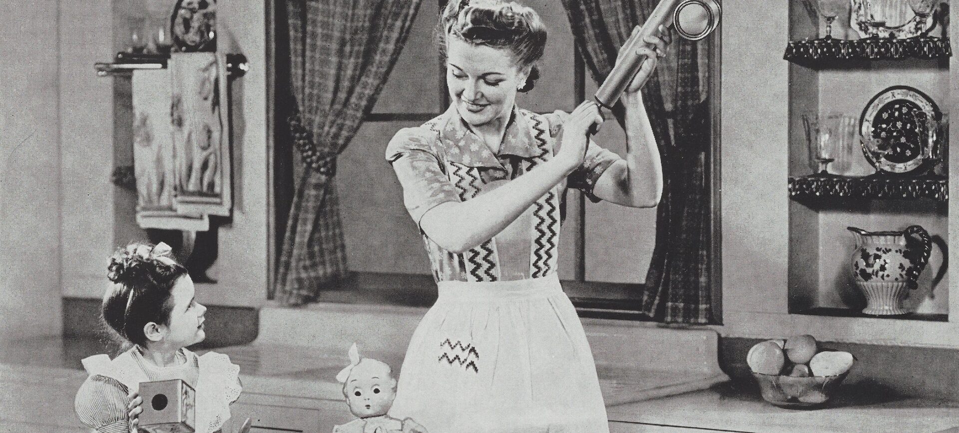 woman holding am insect sprayer while a child looks on