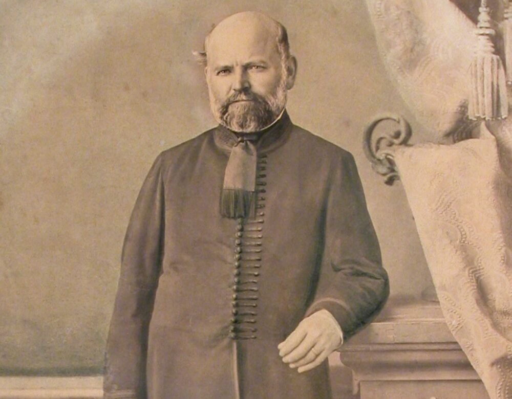 sepia toned portrait of a man in coat and riding boots