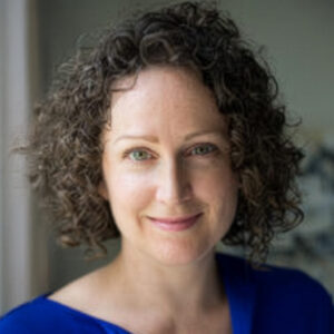 Woman with curly hair wearing blue, indoors