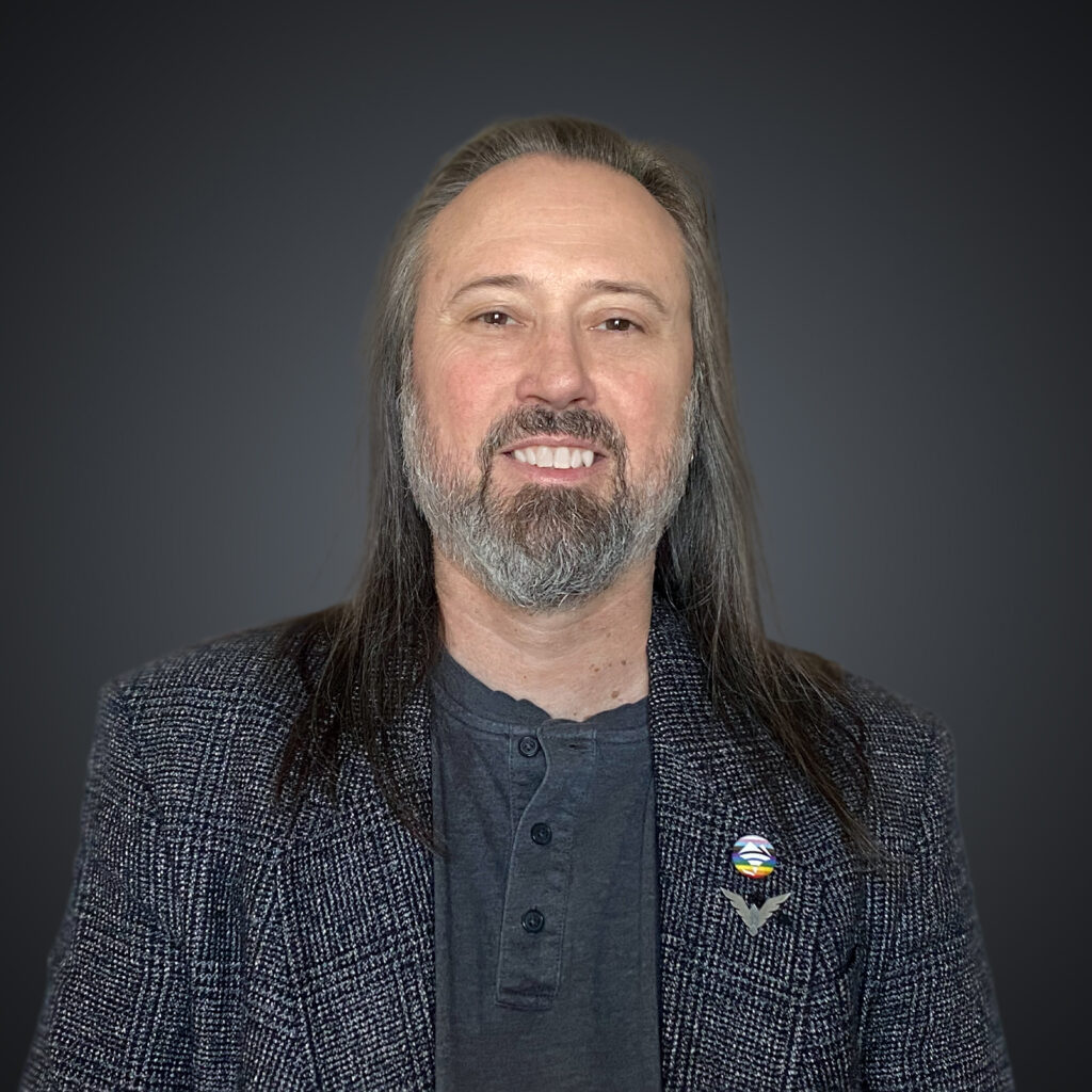 Studio portrait of Brian Schmidt with beard and gray attire