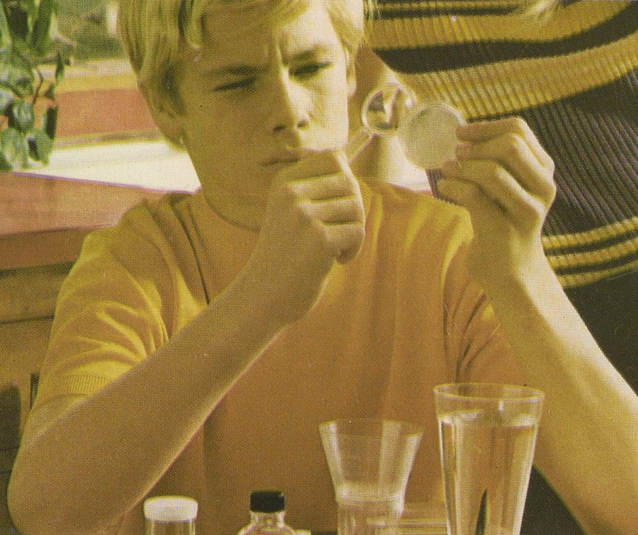 A boy examines a petri dish with a magnifying glass on the cover of this instructional booklet from the Johnny Horizon Environmental Test Kit, 1971.