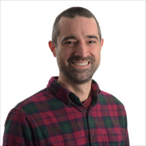 studio portrait on white background of a smiling man in red and black buffalo plaid