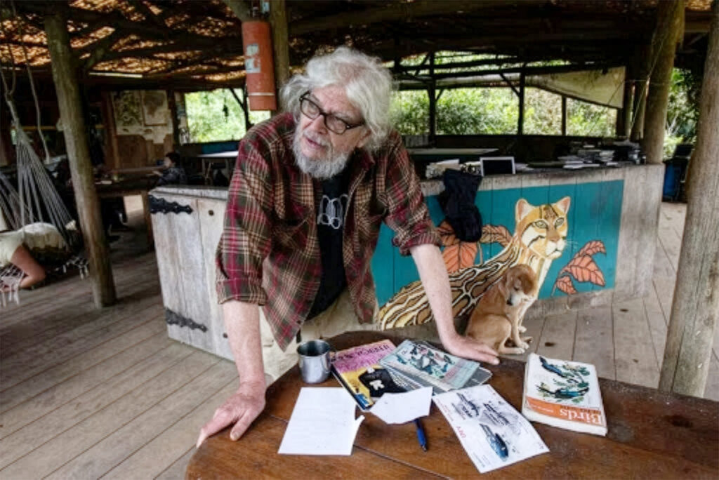 Color photo of an older man leaning over a a table in an open-air building