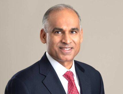 Studio portrait of Bob Patel wearing black blazer, white shirt, and red tie