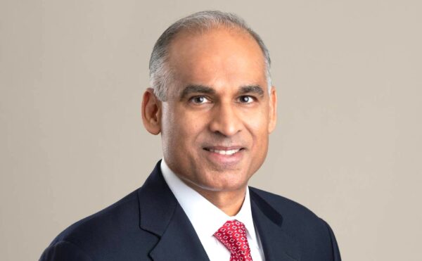 Studio portrait of Bob Patel wearing black blazer, white shirt, and red tie