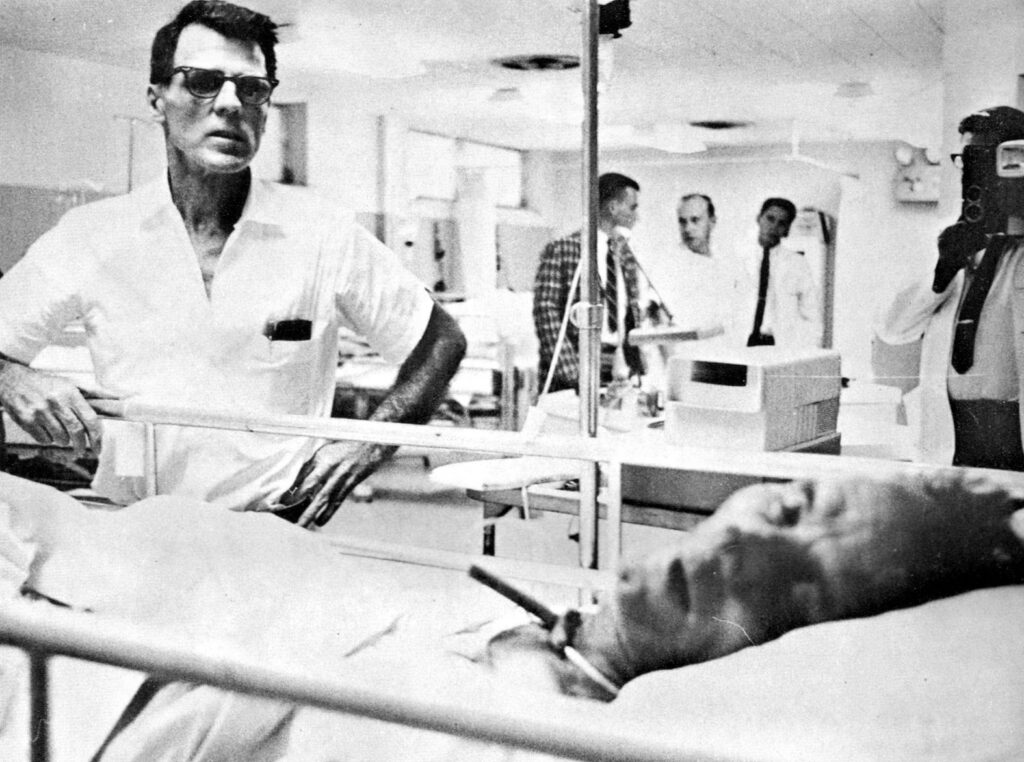 Man standing beside of another man in a hospital ward