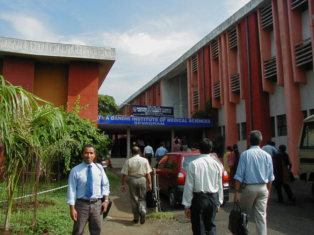 Undated photograph of Lee Riley (left) in front of the Mahatma Gandhi Institute of Medical Sciences in India