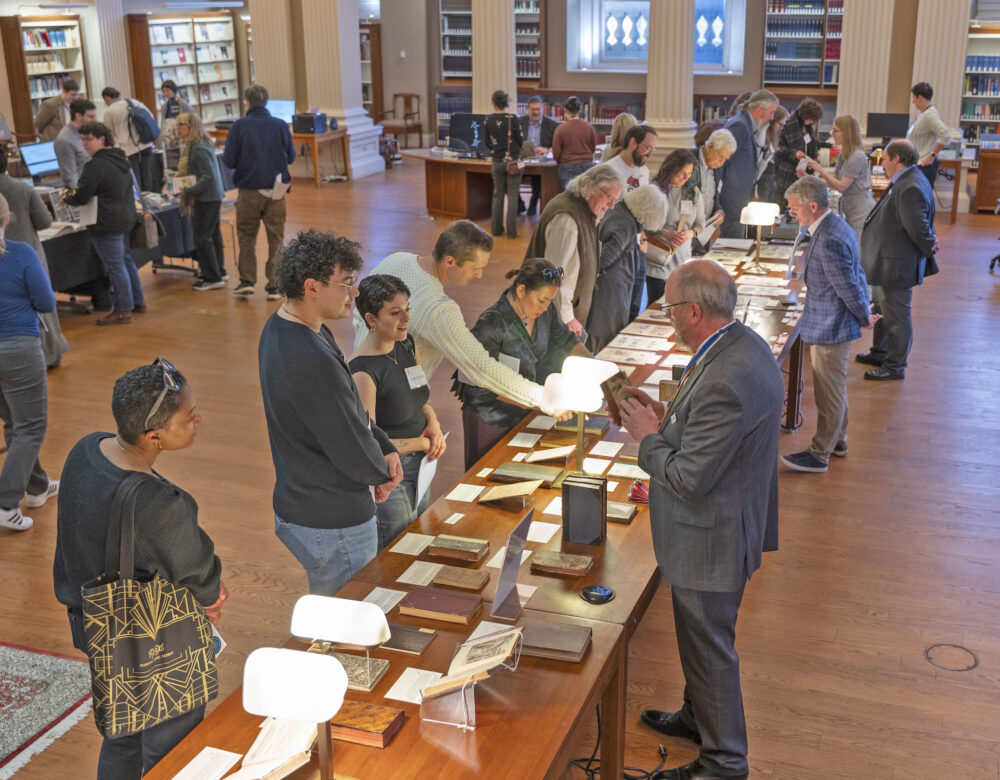 visitors and librarians looking at book and archive exhibits on a long table