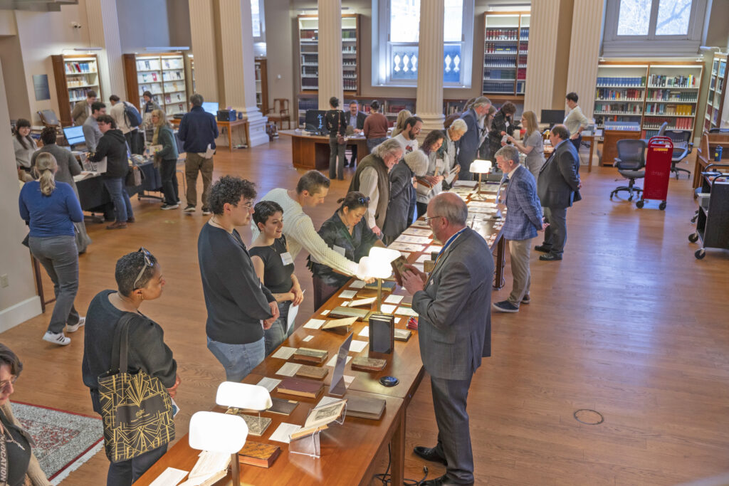 visitors and librarians looking at book and archive exhibits on a long table